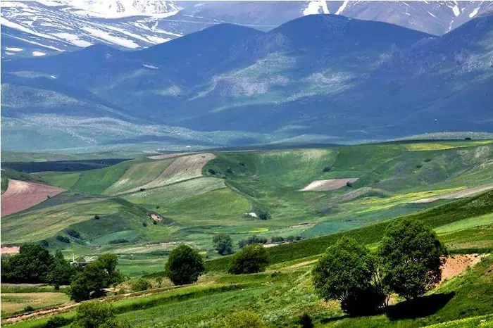 تپه های سرسبز در کنار درختان و کوه های سرسبز برفی روستای روستای قلعه جوق اردبیل، یکی از روستاهای اردبیل 9847957384946